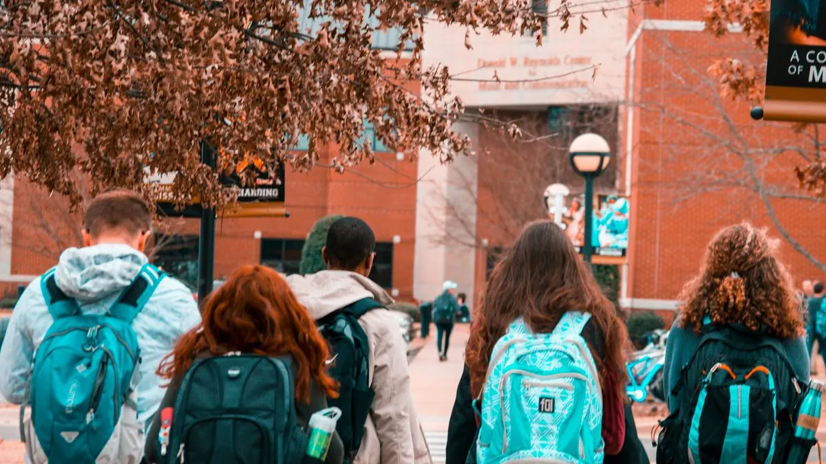 Studenti s batohy kráčejí po univerzitní ulici