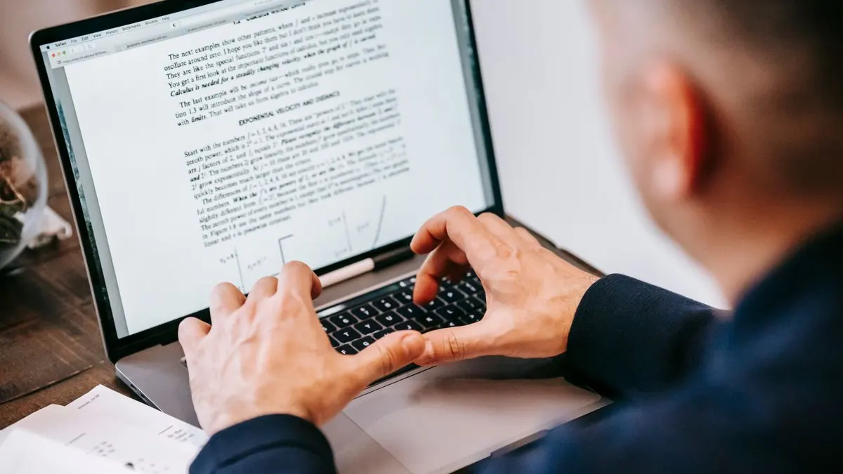 Ruce píšou na notebooku s otevřeným dokumentem