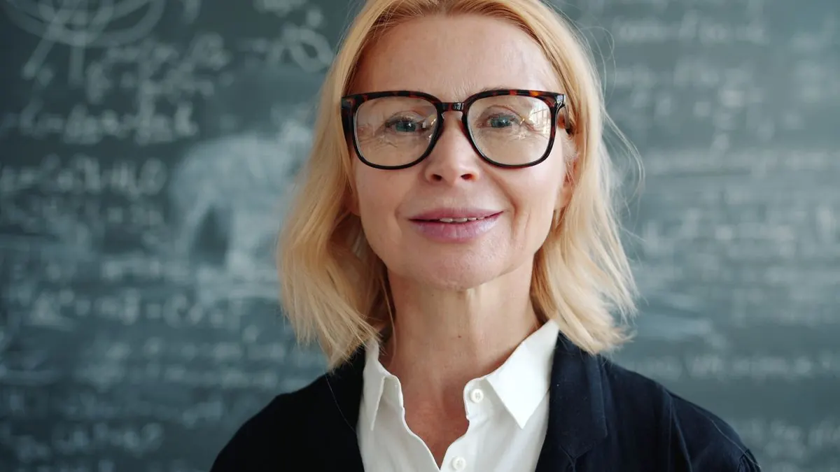 Profesorka s brýlemi stojí před tabulí