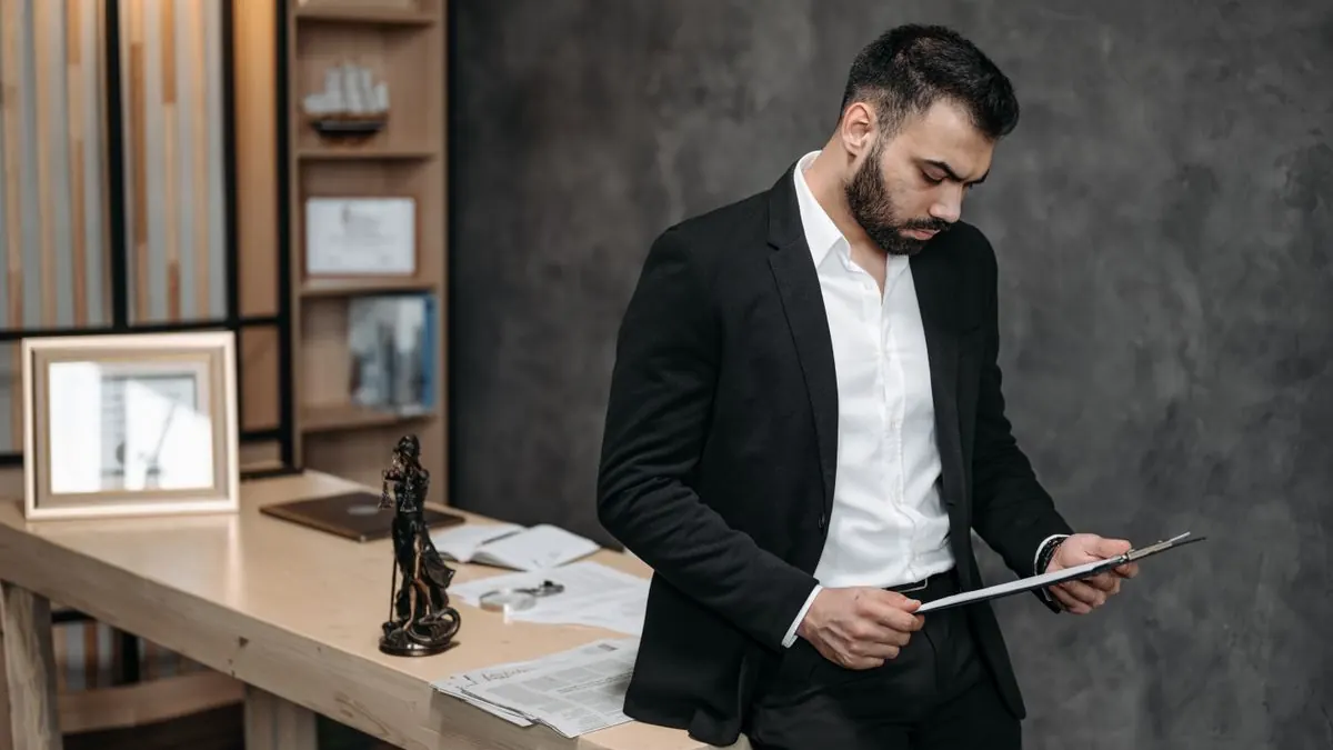 Muž v obleku kontroluje dokumenty s tabletem v ruce