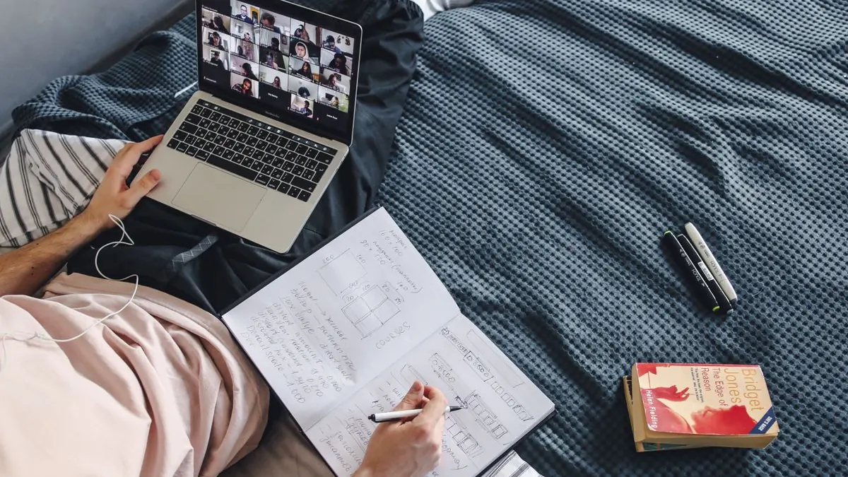 Studentka sleduje online výuku z postele s notebookem