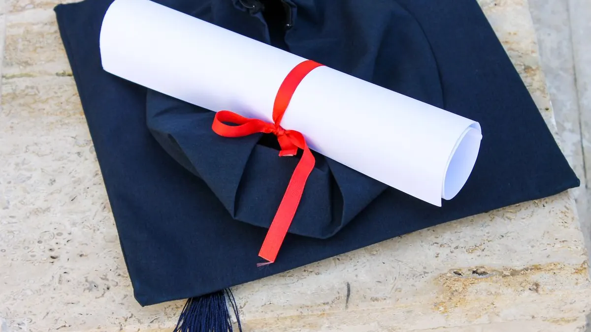 Promoční čepice se svinutým diplomem staženým páskou