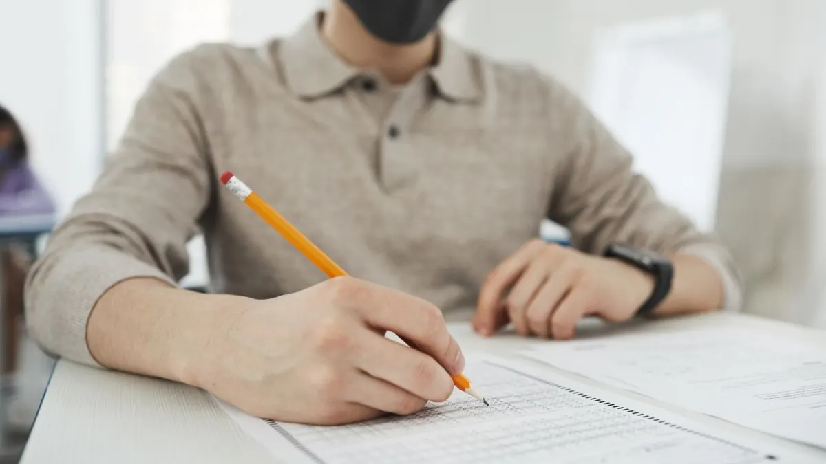 Muž soustředěně píše zkouškový test