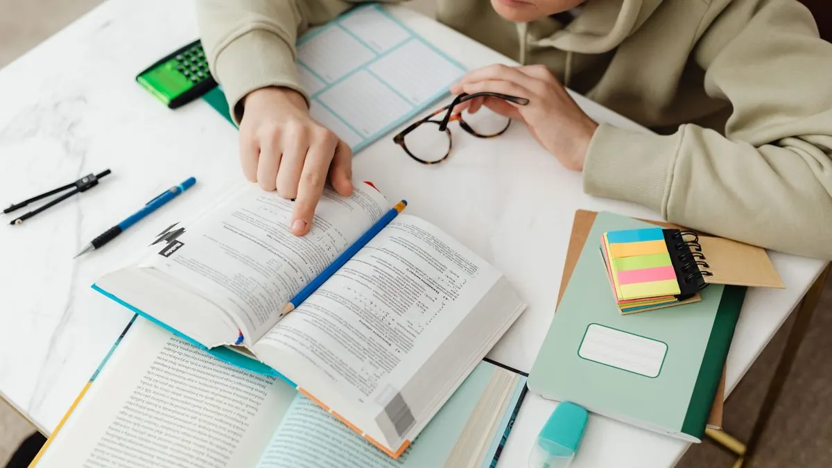 Student pracuje s kalkulačkou a poznámkami na stole